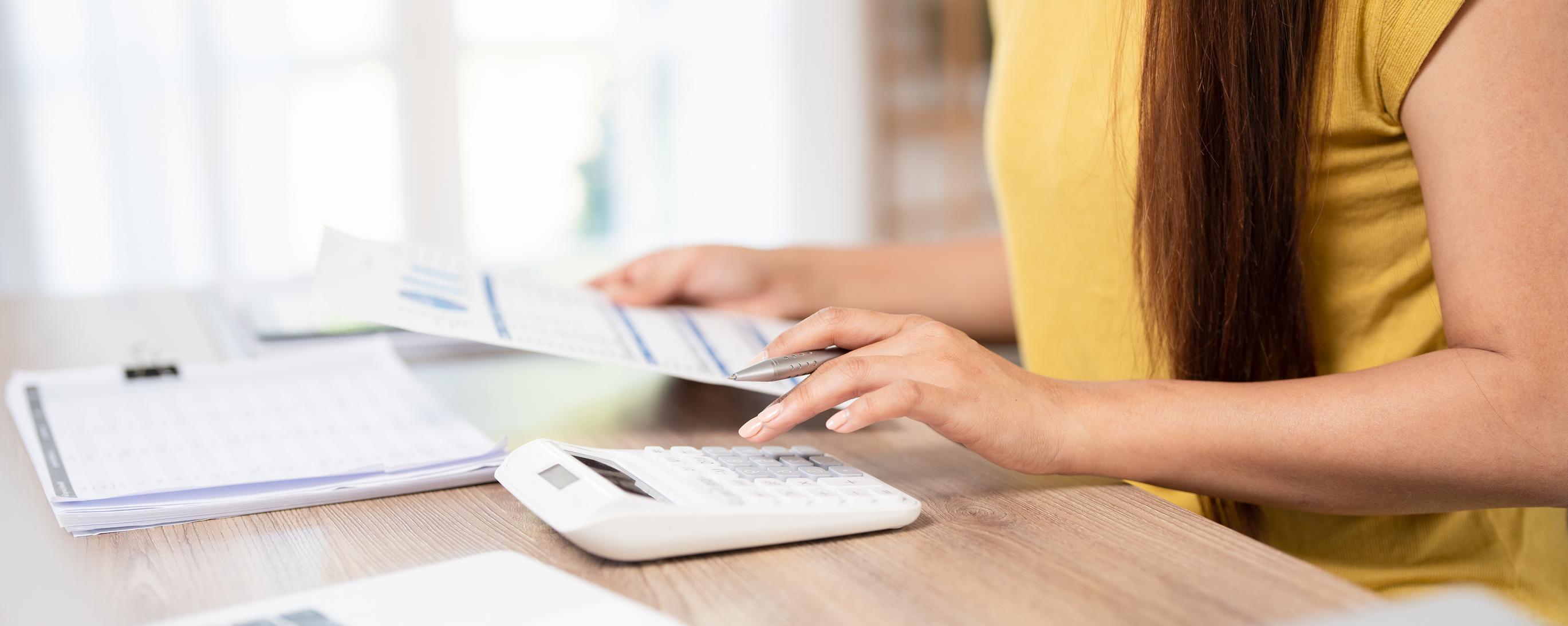 Woman using a calculator and reviewing financial documents.