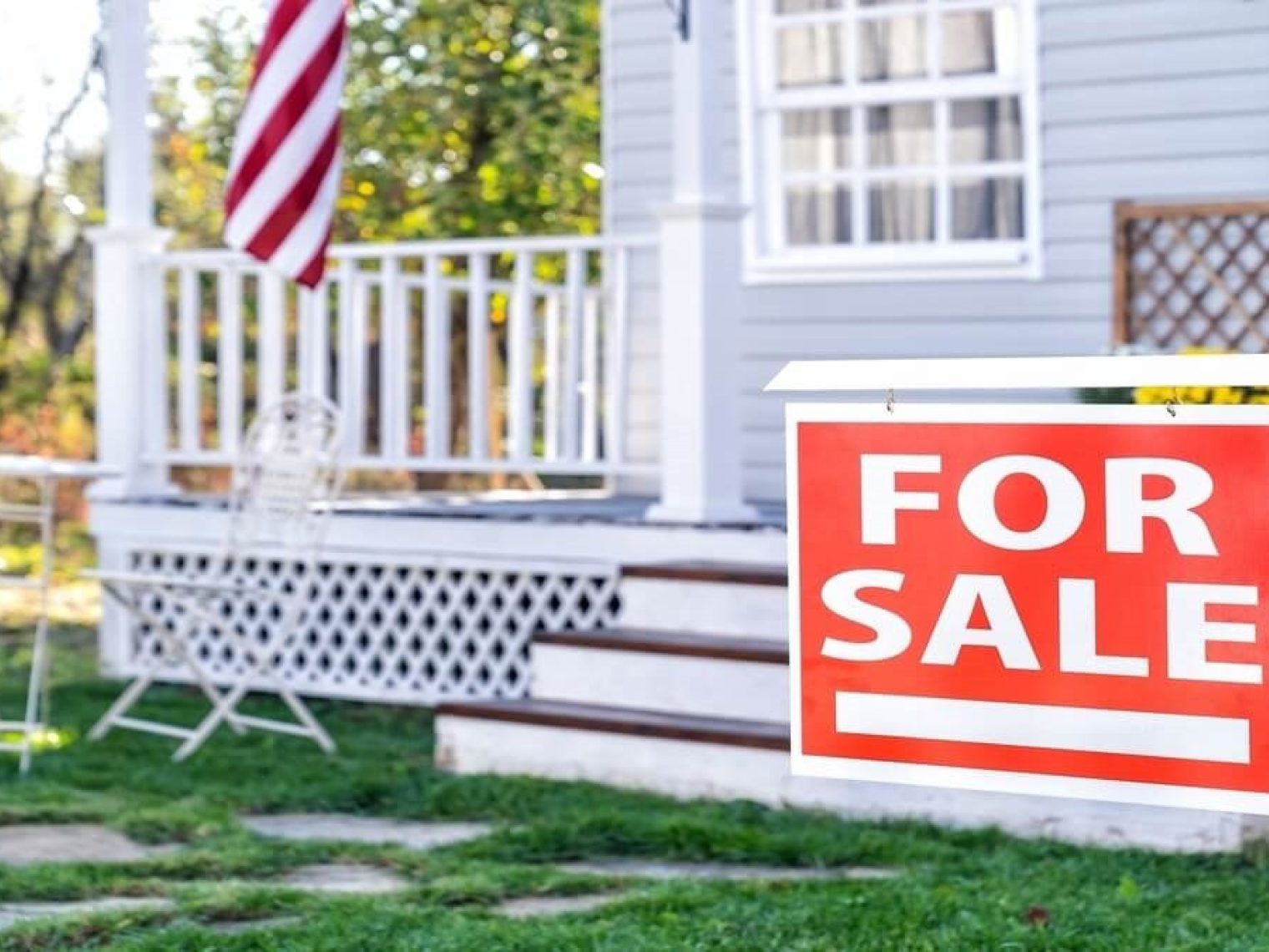 Red For Sale sign in front of a white house.