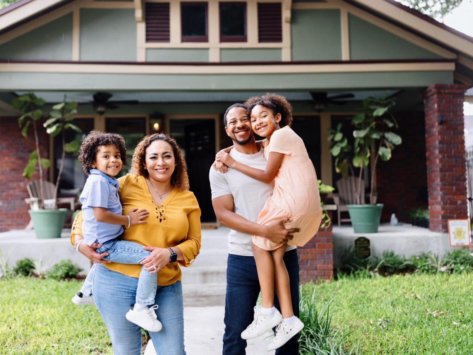 An African American family standing outside their home.