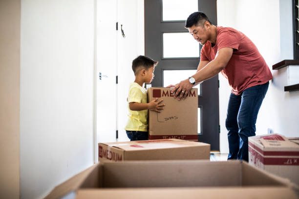 Father hands moving box to son in hallway