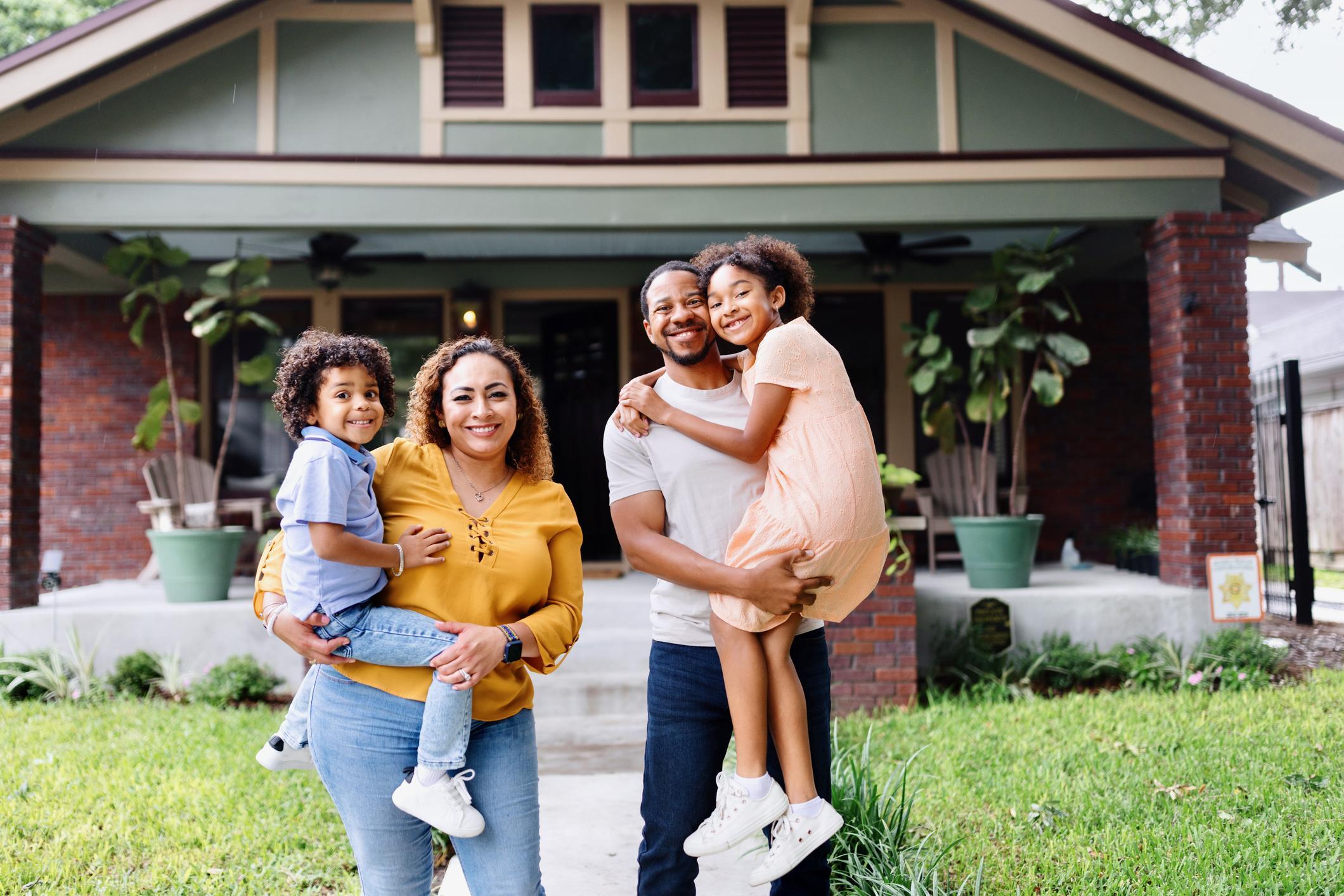 An African American family standing outside their home.