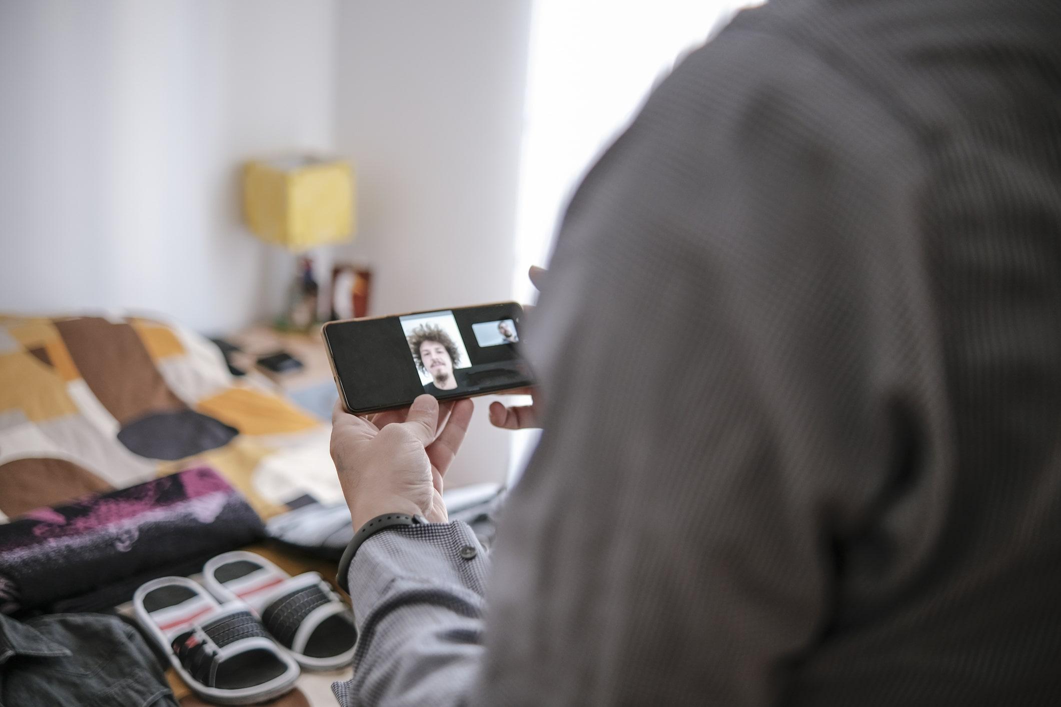 Overseas service member video chatting with loan officer. A packed, open suitcase can be seen in the background.